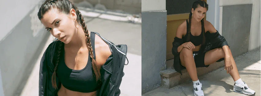 Mujer joven con trenzas luciendo ropa deportiva negra y chaqueta, posando en exteriores urbanos soleados