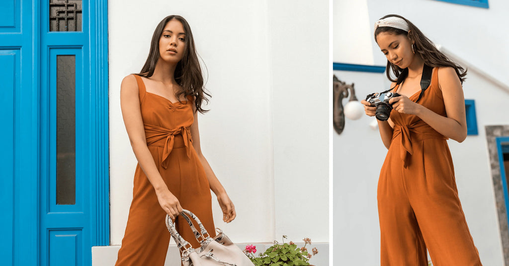 Mujer en mono marrón tomando fotos con cámara vintage junto a puerta azul y flores