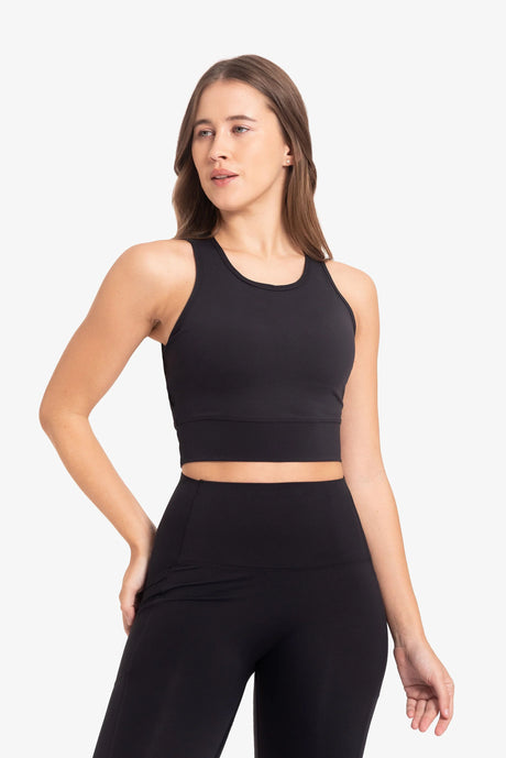 Mujer usando conjunto deportivo negro de top sin mangas y leggings en fondo blanco