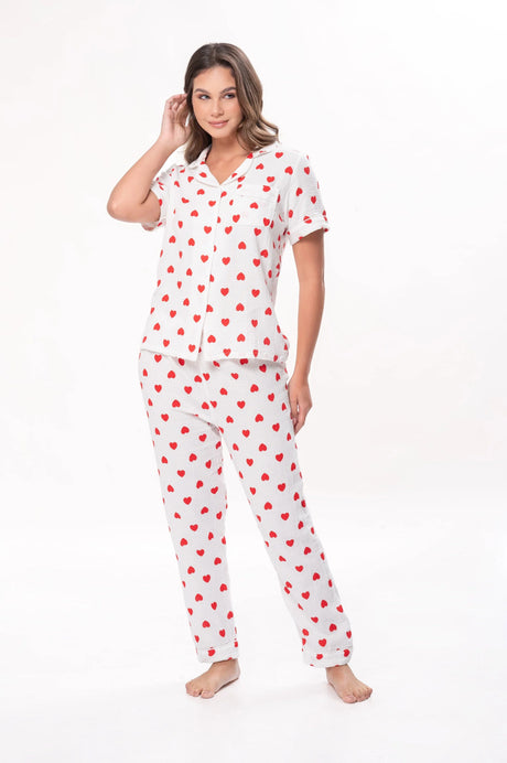 Mujer en pijama blanco con estampado de corazones rojos, posando sobre fondo blanco